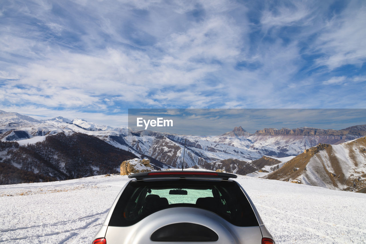 Rear view of the unrecognizable upper part of an suv high in the mountains in winter against 