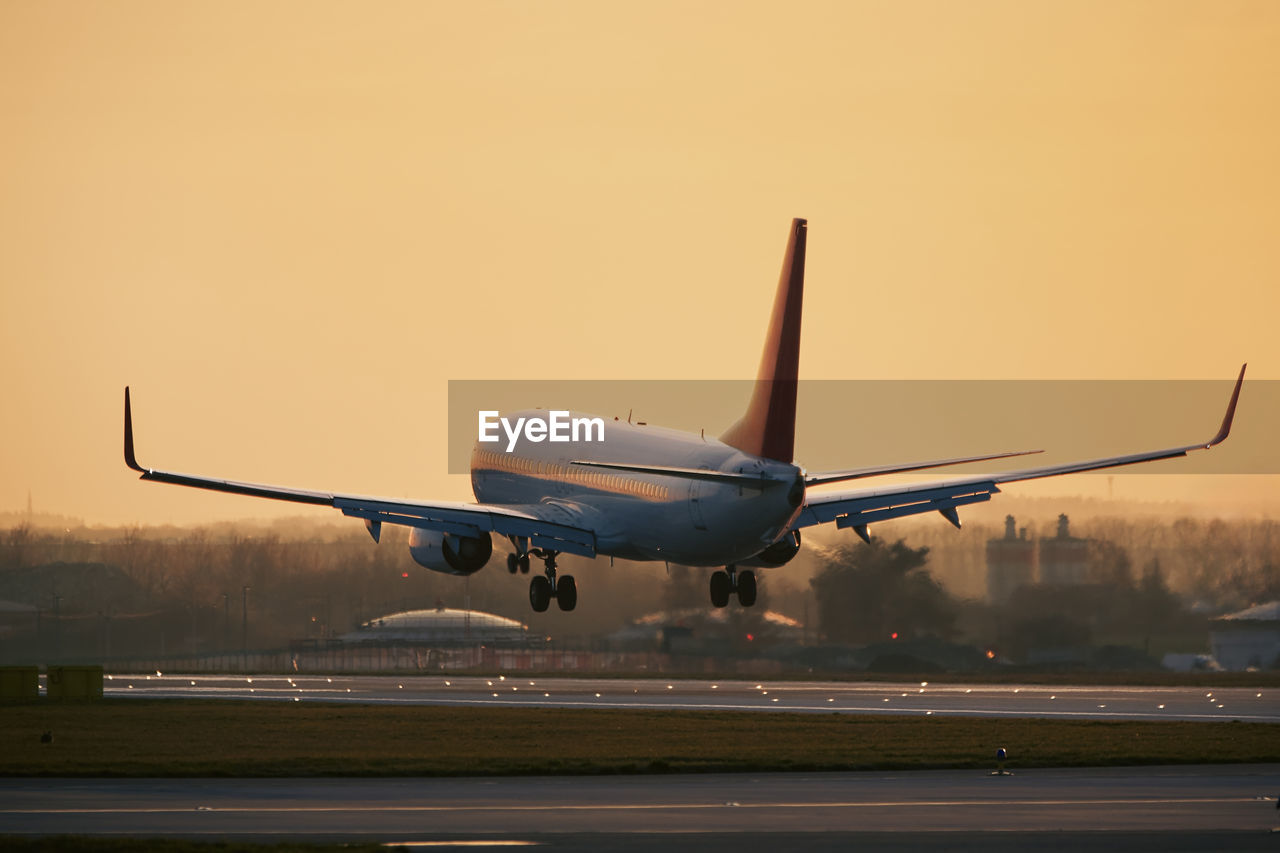 Airplane approaching for landing on airport runway. passenger plane at golden light of sunset. 