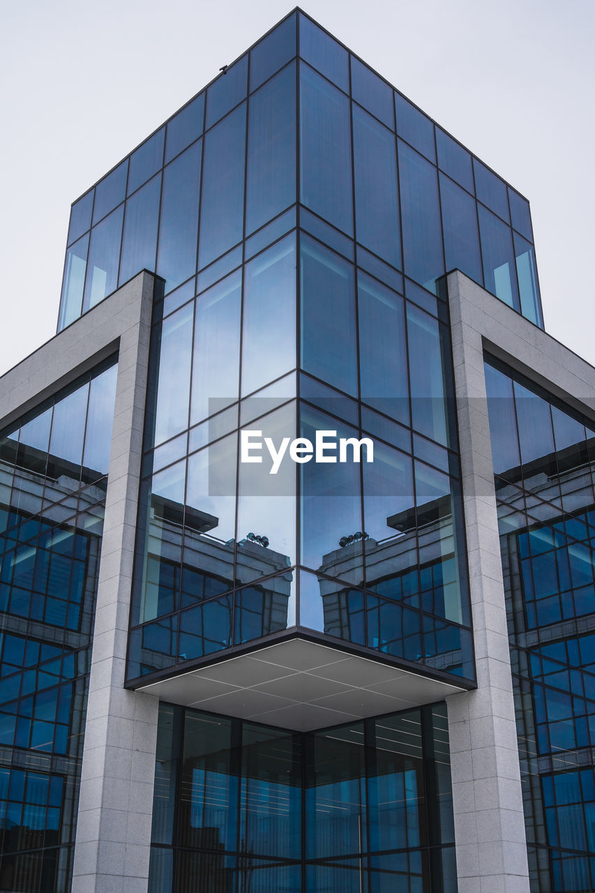 Low angle view of glass building against sky