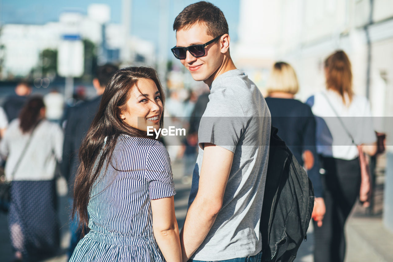 Portrait of smiling young couple standing on sunny day