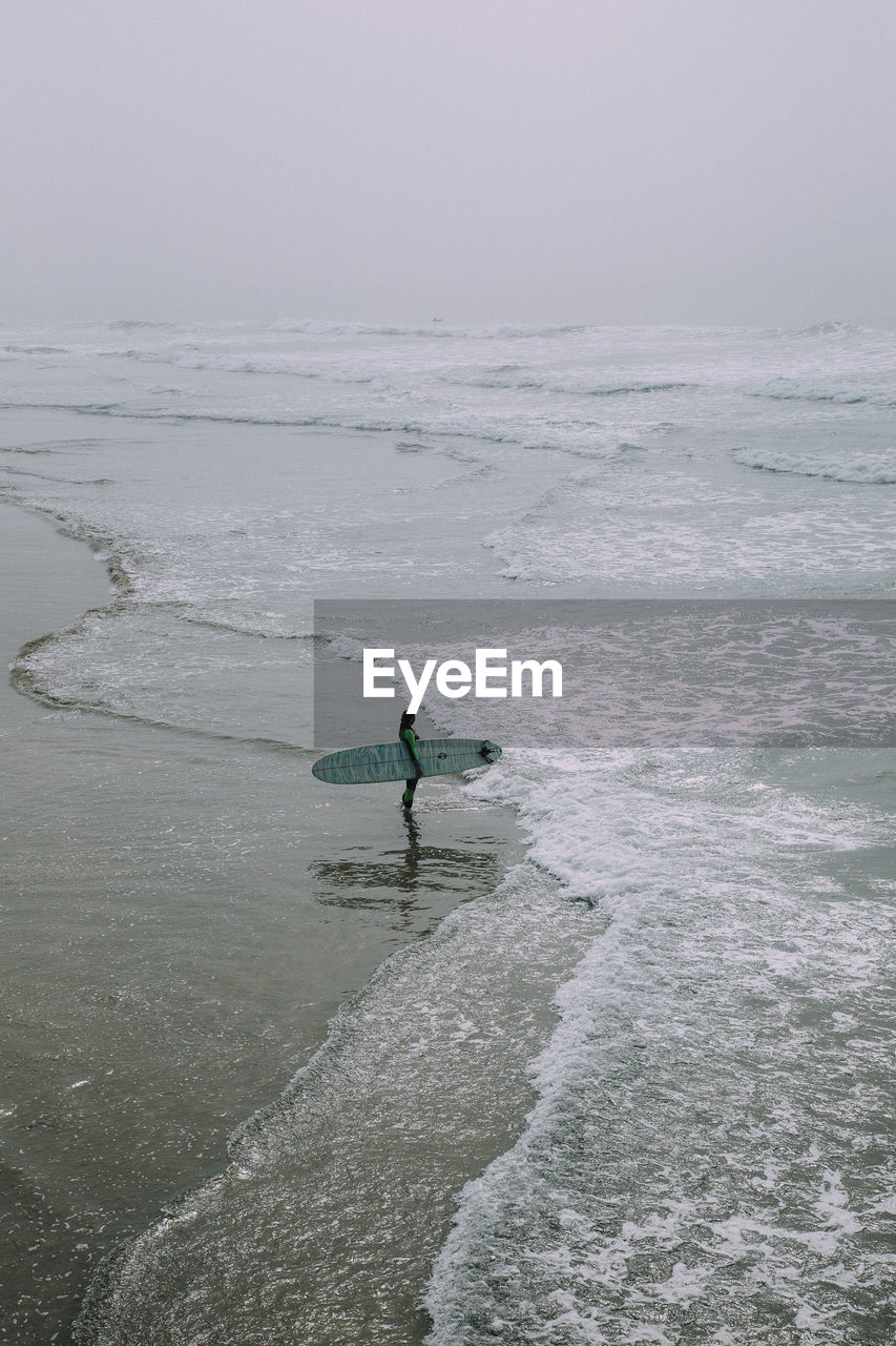 Woman with surfboard standing at beach