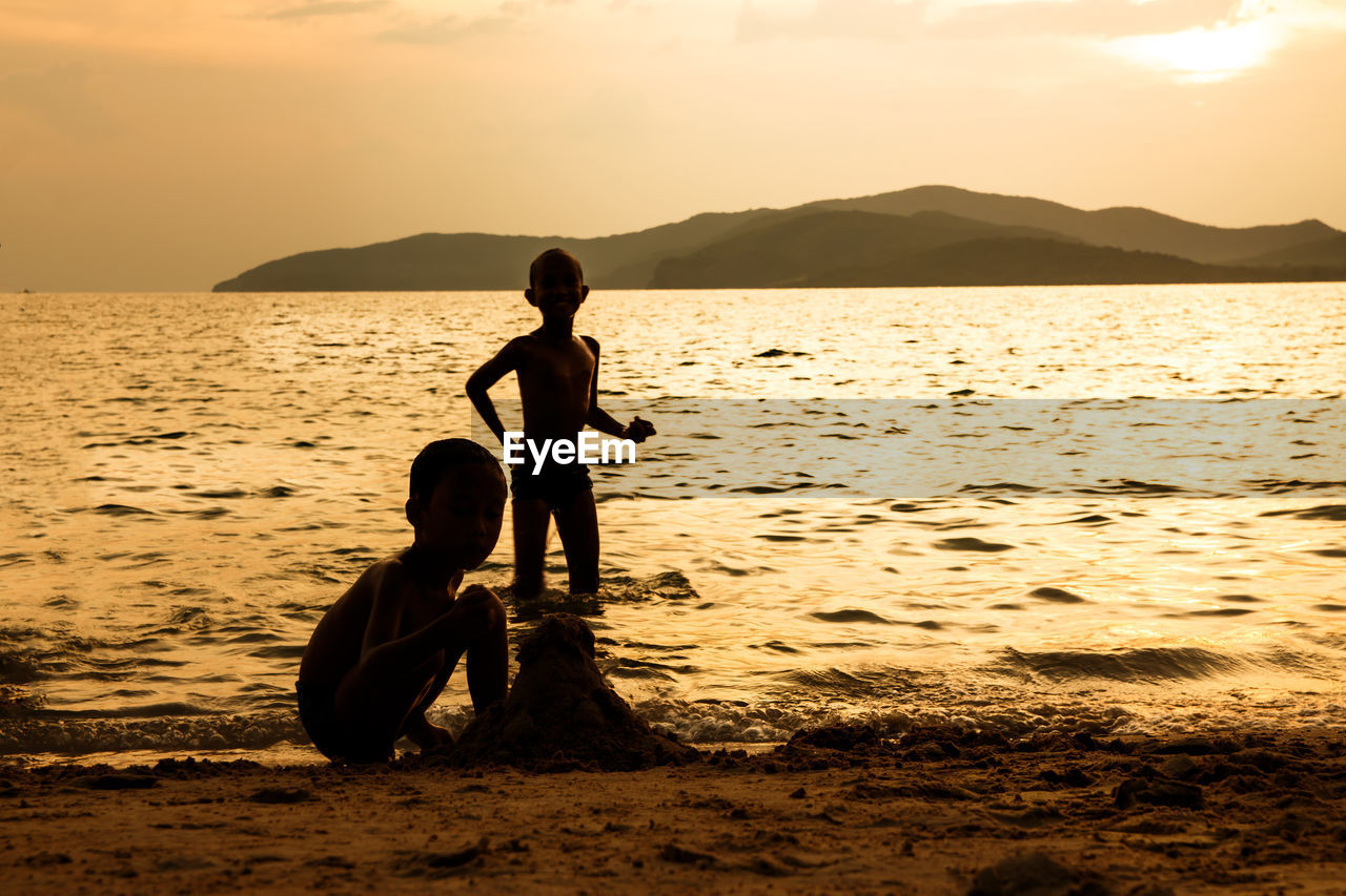 CHILDREN ON BEACH AGAINST SKY