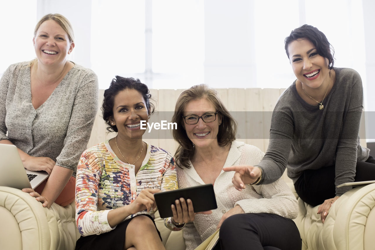 Portrait of happy businesswomen on sofa in creative office