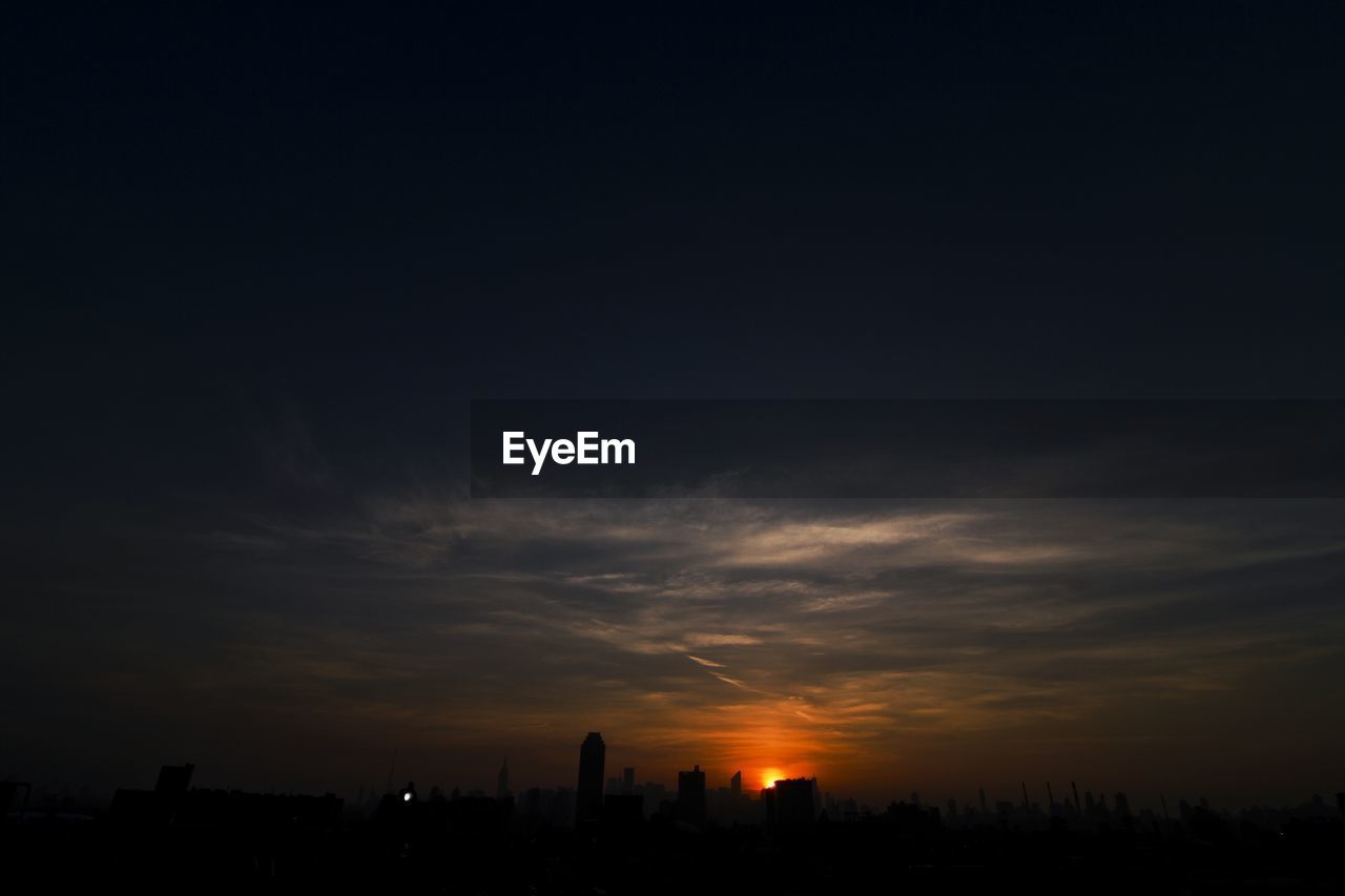 SILHOUETTE BUILDINGS AGAINST SKY DURING SUNSET IN CITY