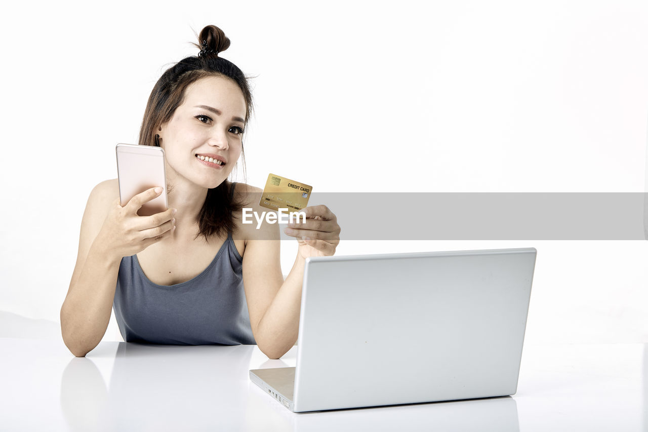 PORTRAIT OF SMILING YOUNG WOMAN USING PHONE