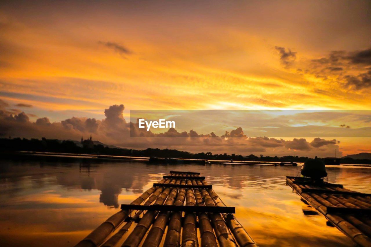 Pier over lake against sky during sunset