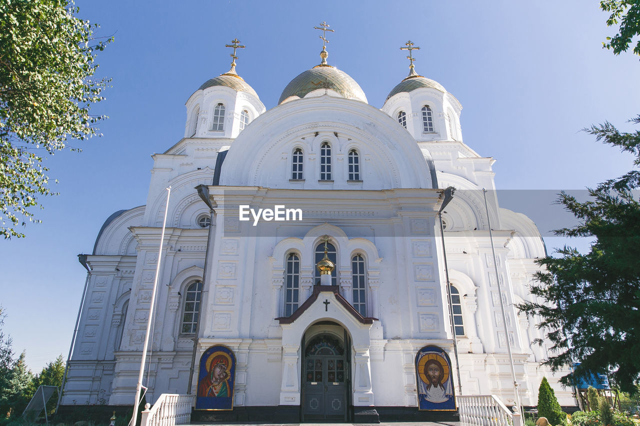 religion, architecture, belief, place of worship, building exterior, built structure, spirituality, travel destinations, building, nature, tree, dome, plant, catholicism, sky, travel, day, arch, cross, facade, no people, tourism, history, blue, outdoors, low angle view, the past, city, white, worship, sunny, sunlight