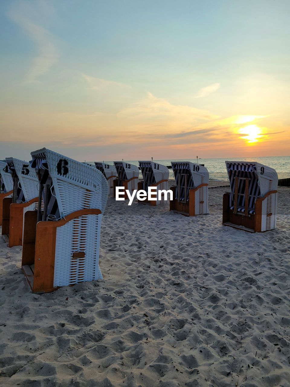 HOODED BEACH CHAIRS ON SAND AGAINST SKY