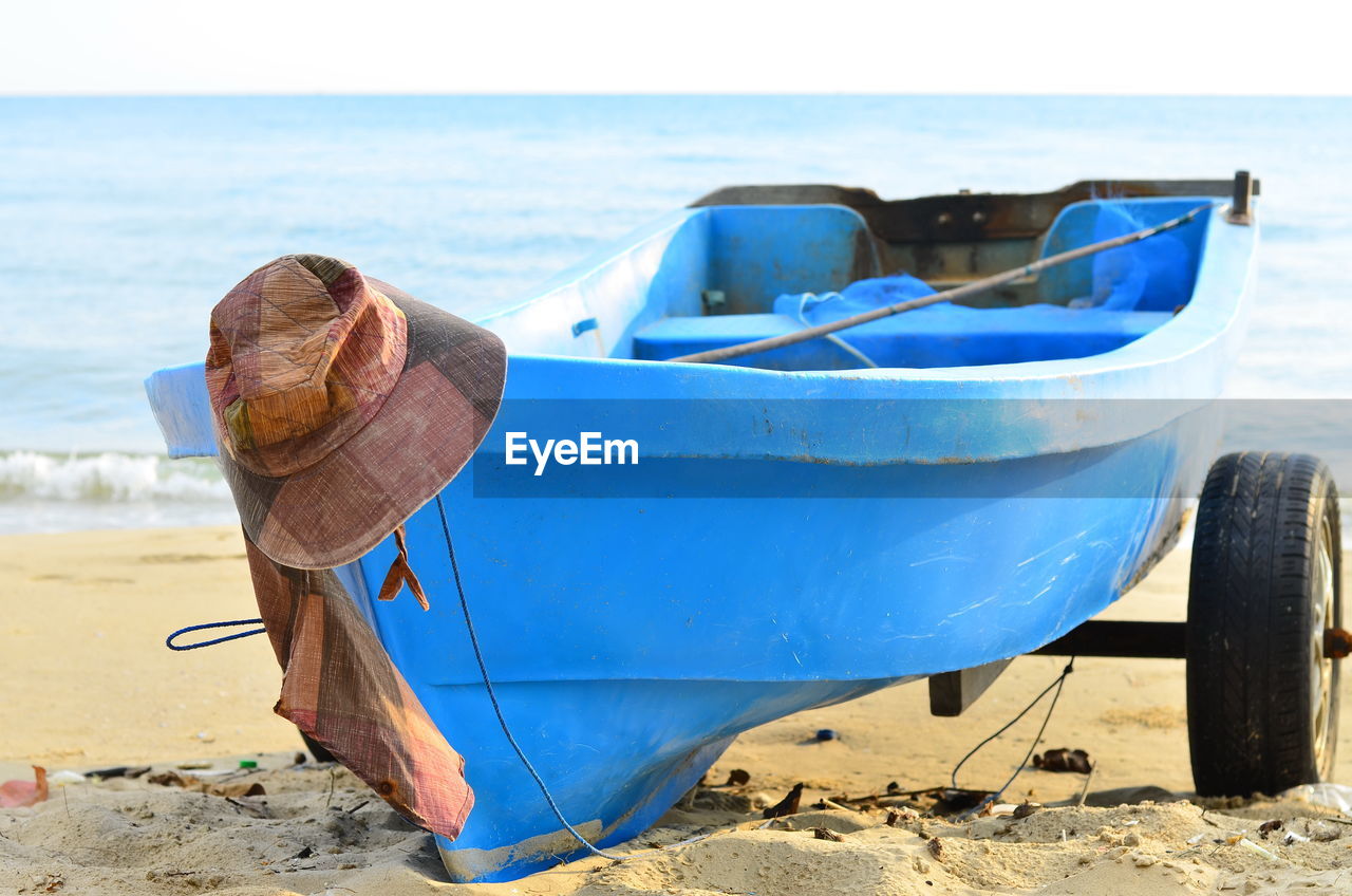 Boat moored on beach against sky