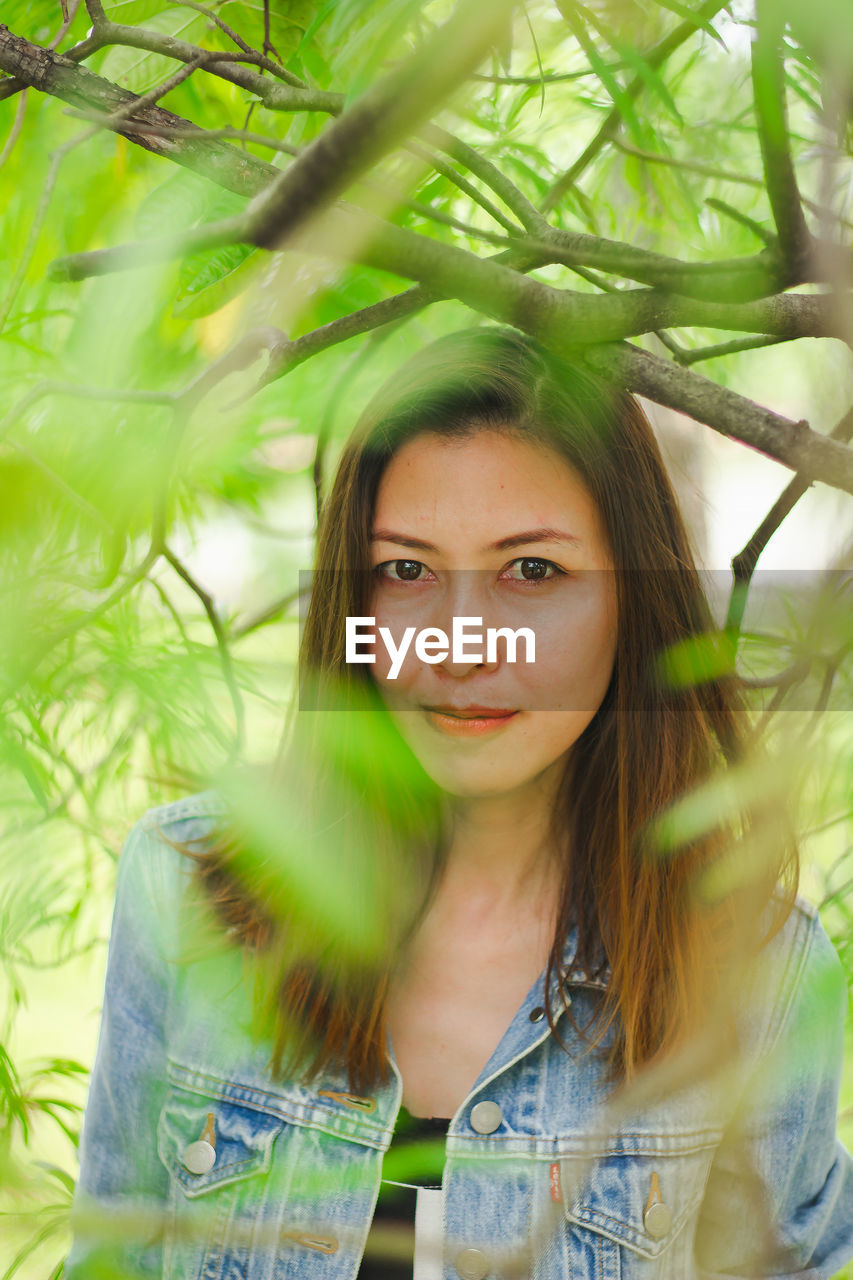 Portrait of beautiful woman standing by plant