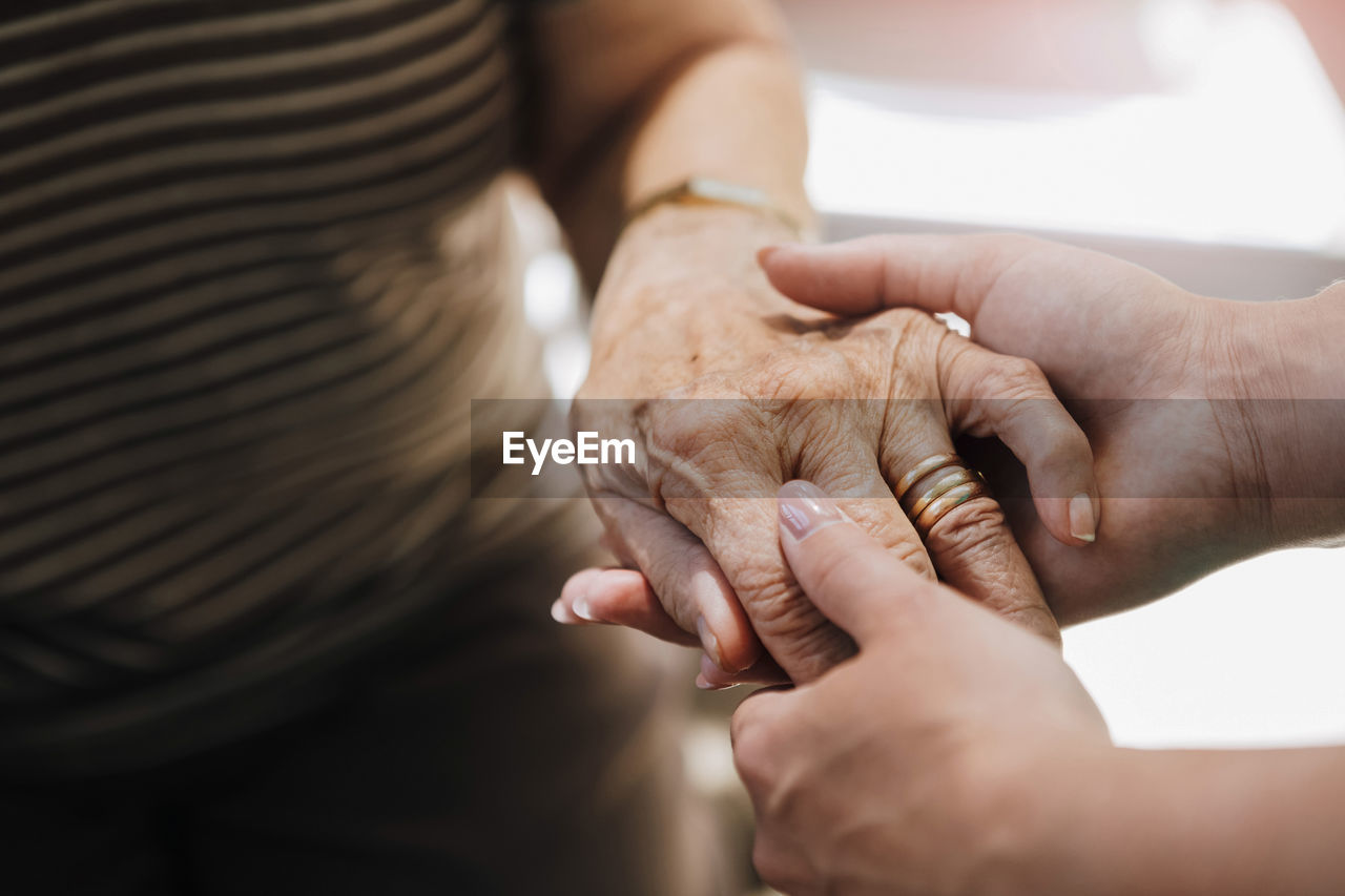 Cropped image of elderly care nurse holding hand of senior woman at nursing home