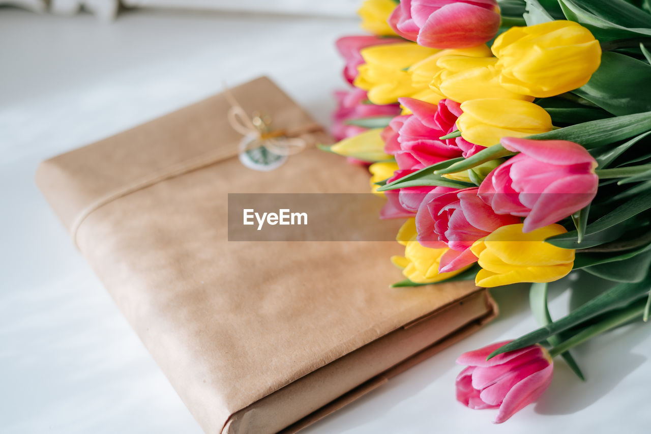 Fresh spring yellow and pink tulips bouquet on white wood table background with copy space for text.