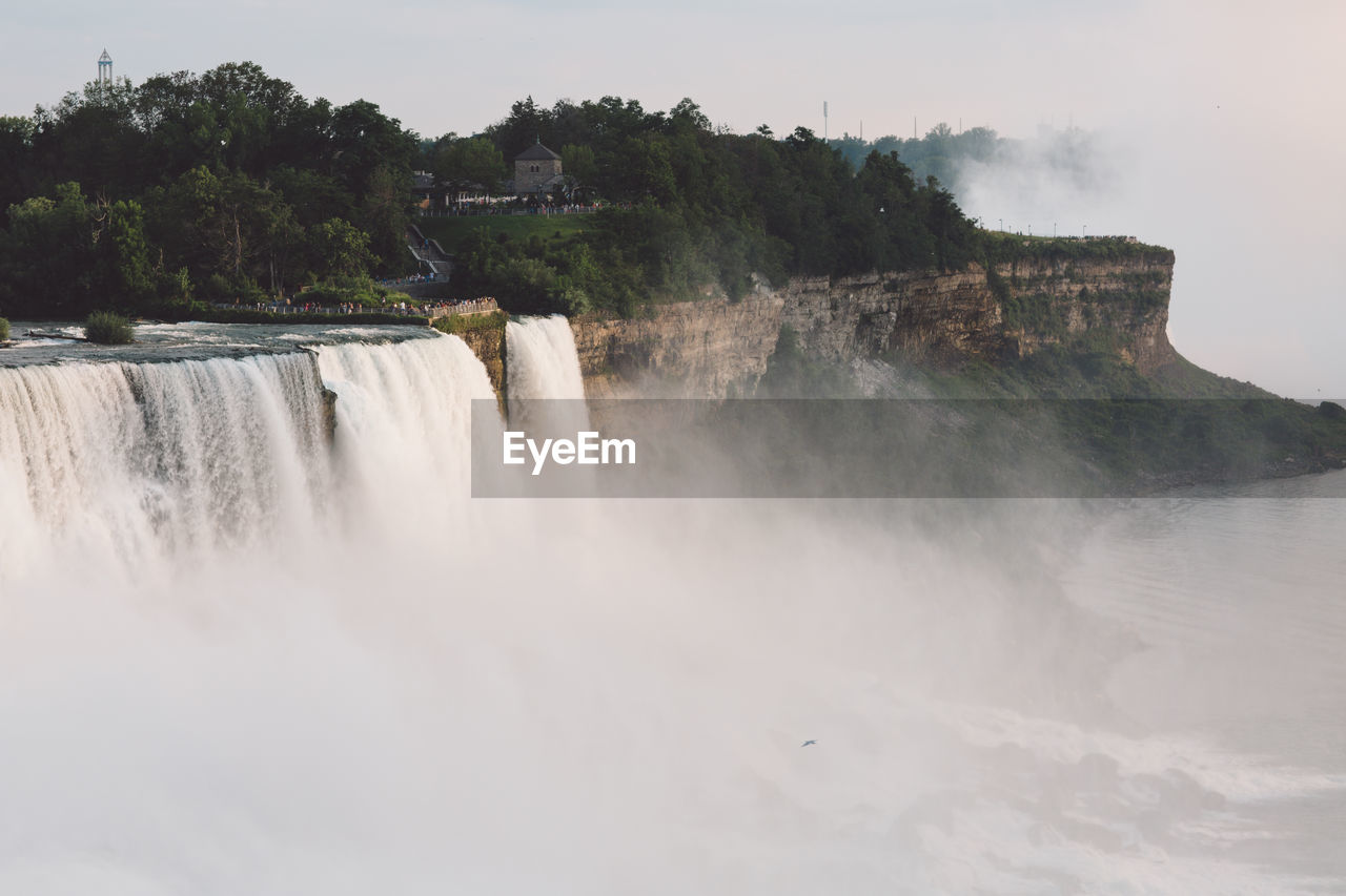 SCENIC VIEW OF WATERFALL AGAINST CLOUDY SKY