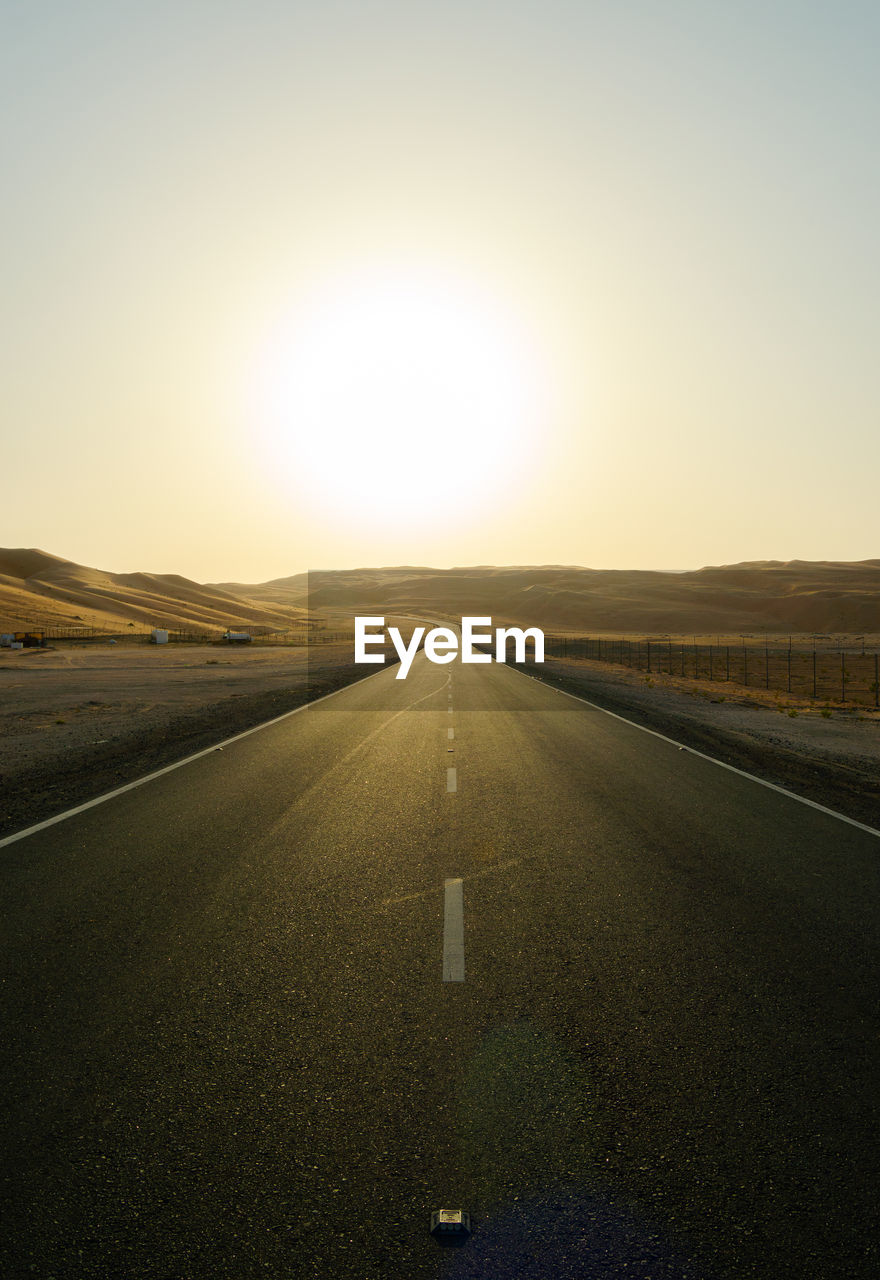 Empty road along landscape at sunset