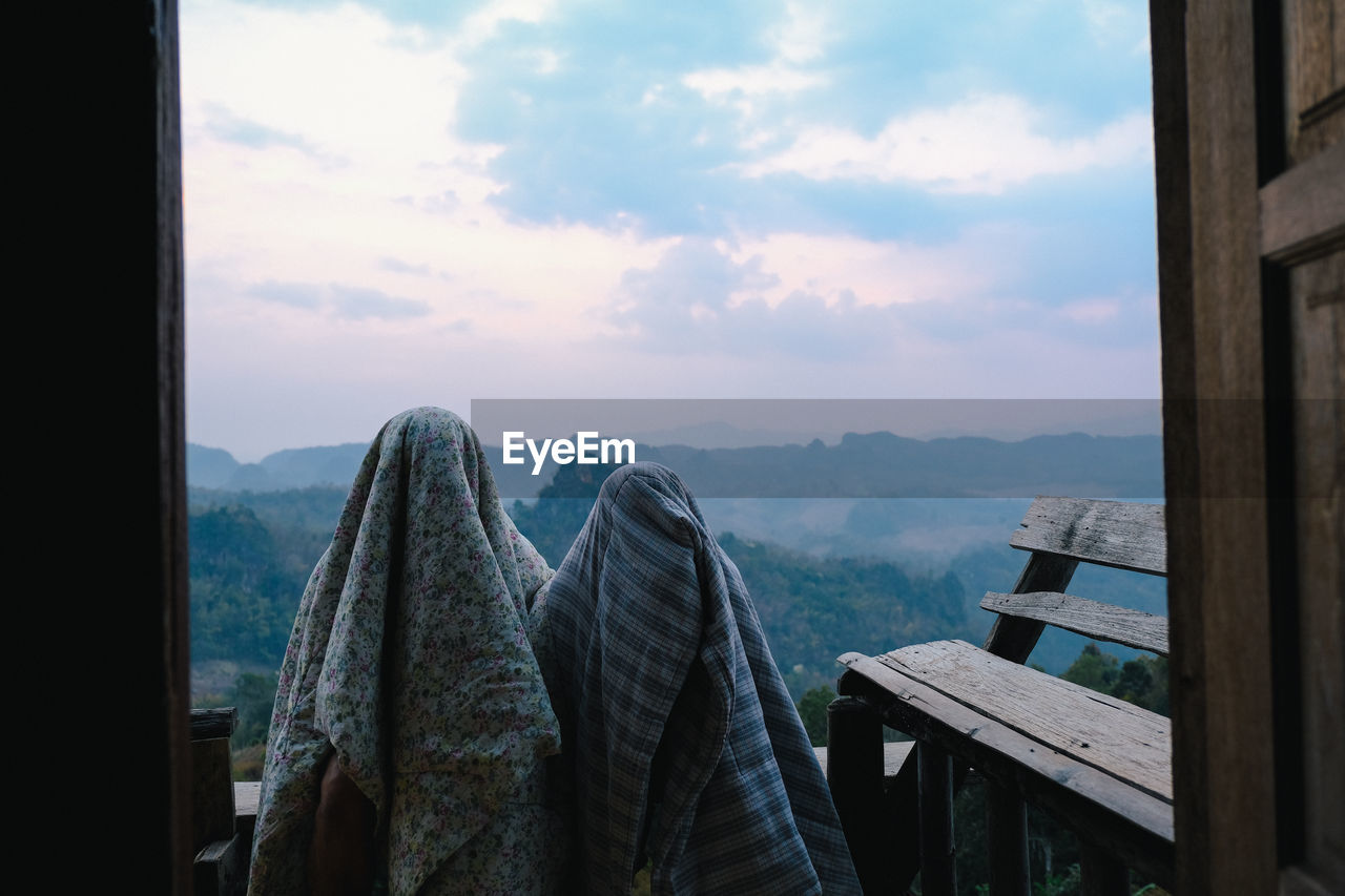 People covered in blanket standing against sky