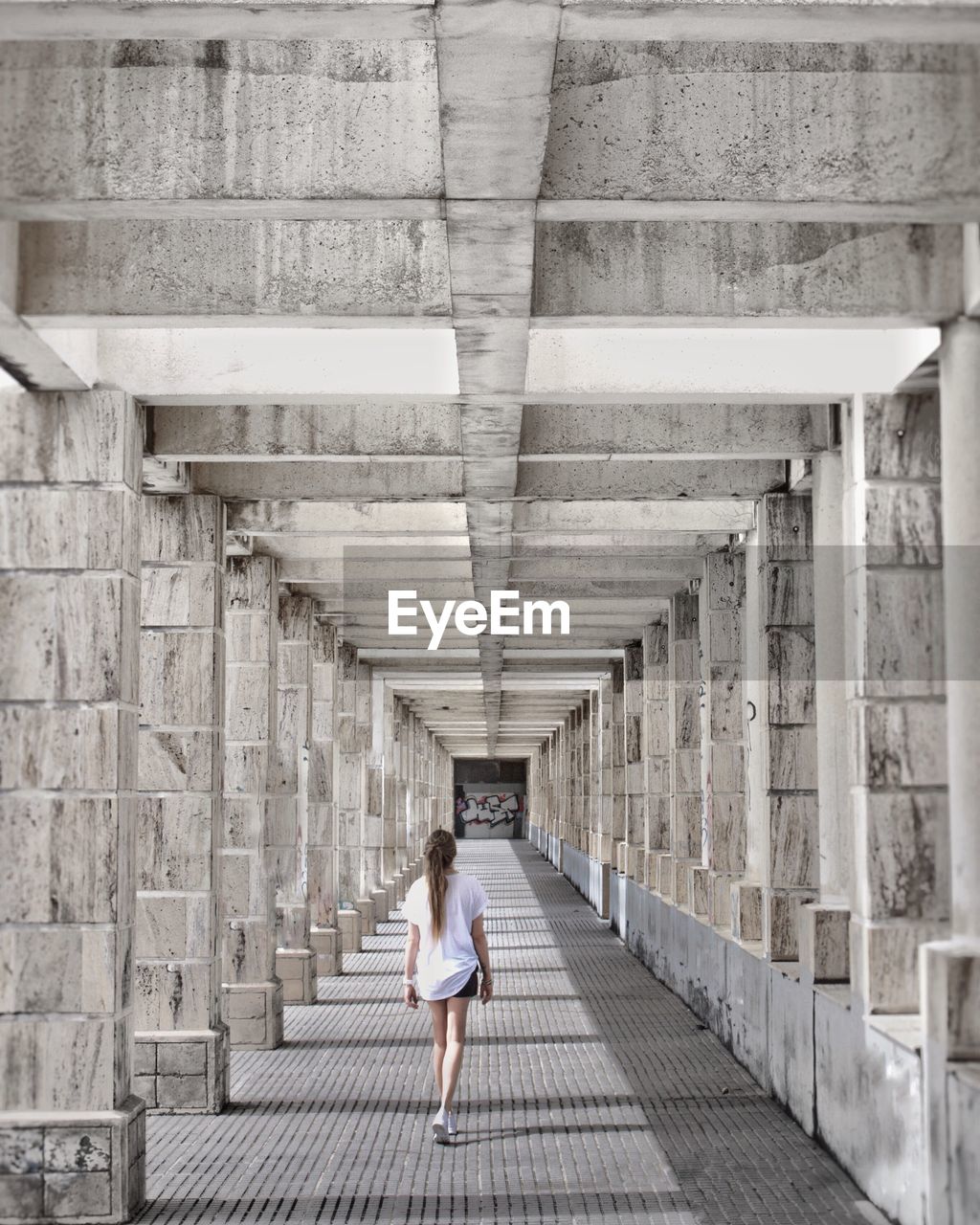 REAR VIEW OF WOMAN WALKING ALONG BRIDGE