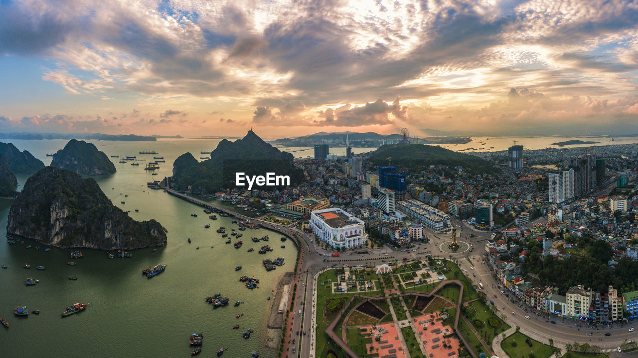 Aerial view of cityscape by bay against sky during sunset
