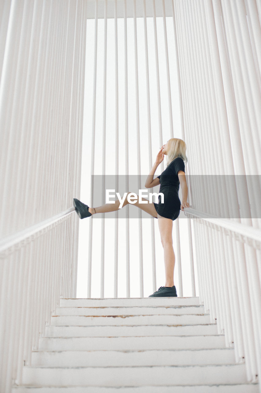 Full length of woman standing on steps amidst railing