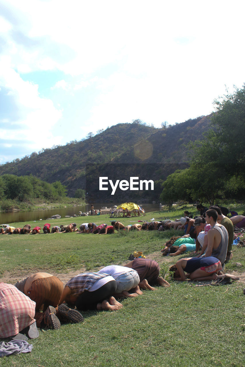 People kneeling and bending on grassy field during religious ceremony