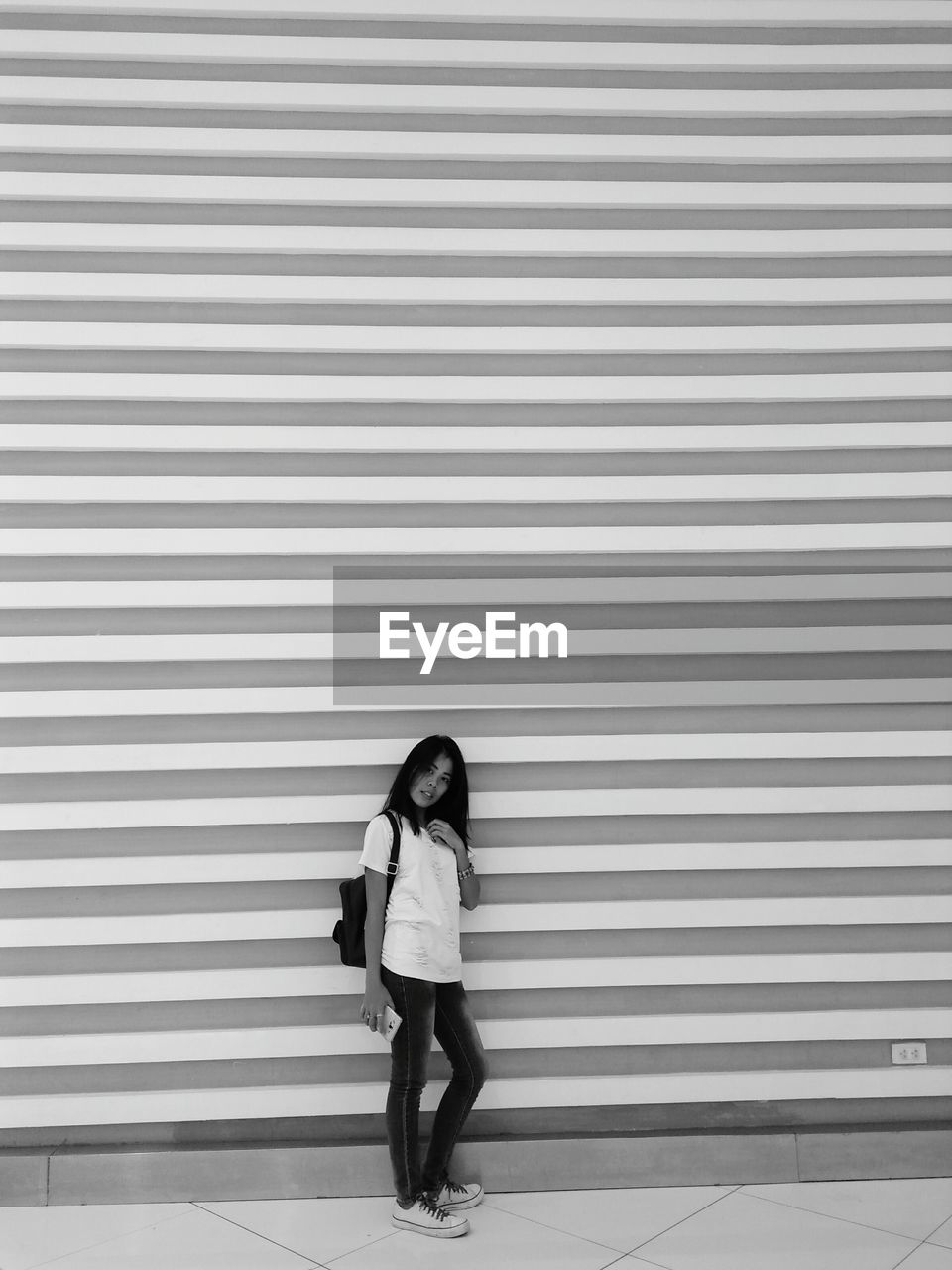 Portrait of young woman standing against patterned wall