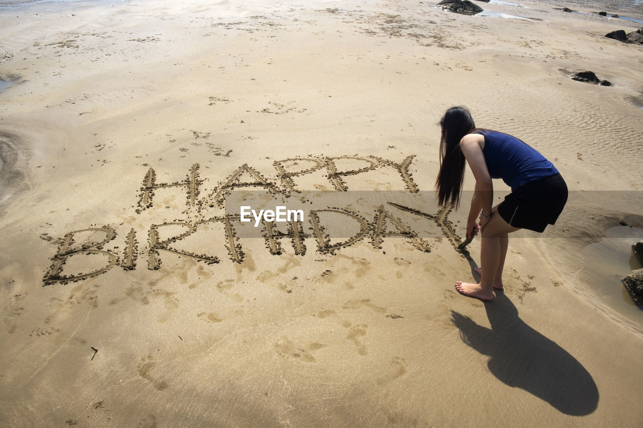 HIGH ANGLE VIEW OF WOMAN WALKING ON BEACH