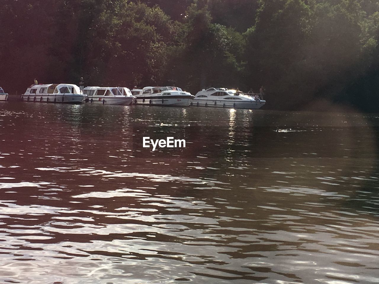 BOATS MOORED IN RIVER AGAINST SKY