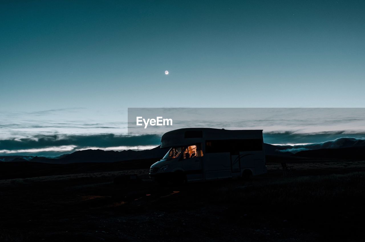 Vehicle on field against sky at dusk