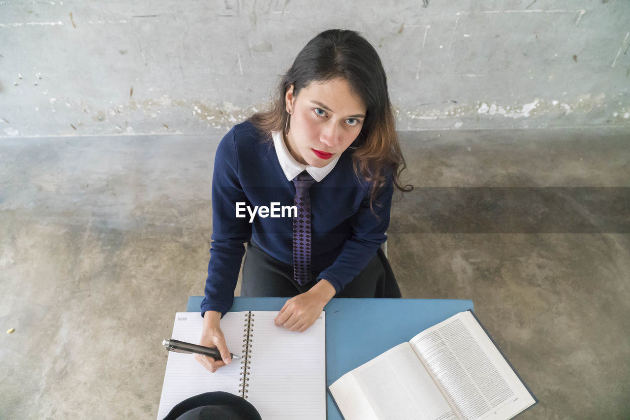 High angle portrait of woman studying while sitting on table