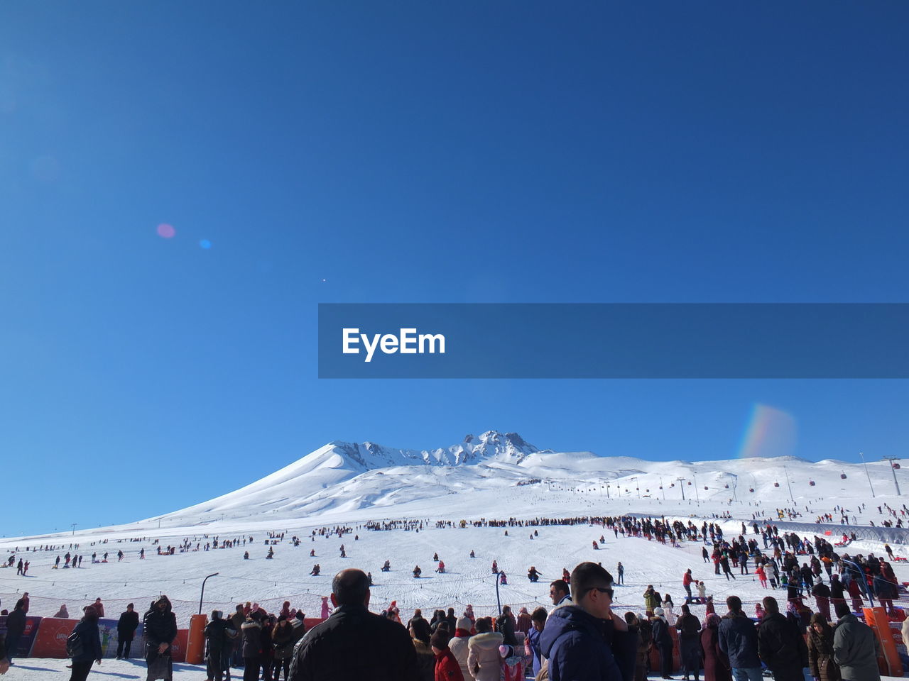 People at town square during winter against clear blue sky