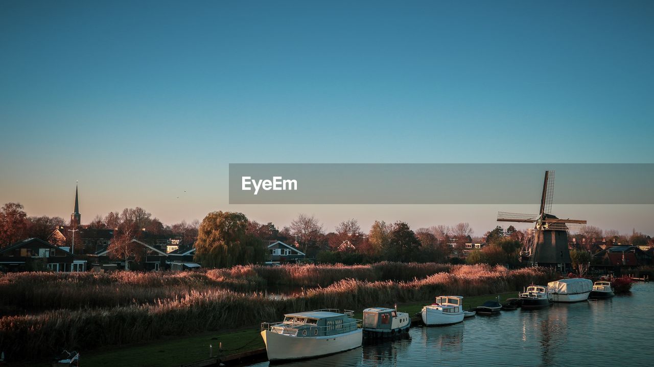 Sailboats moored in lake against clear sky