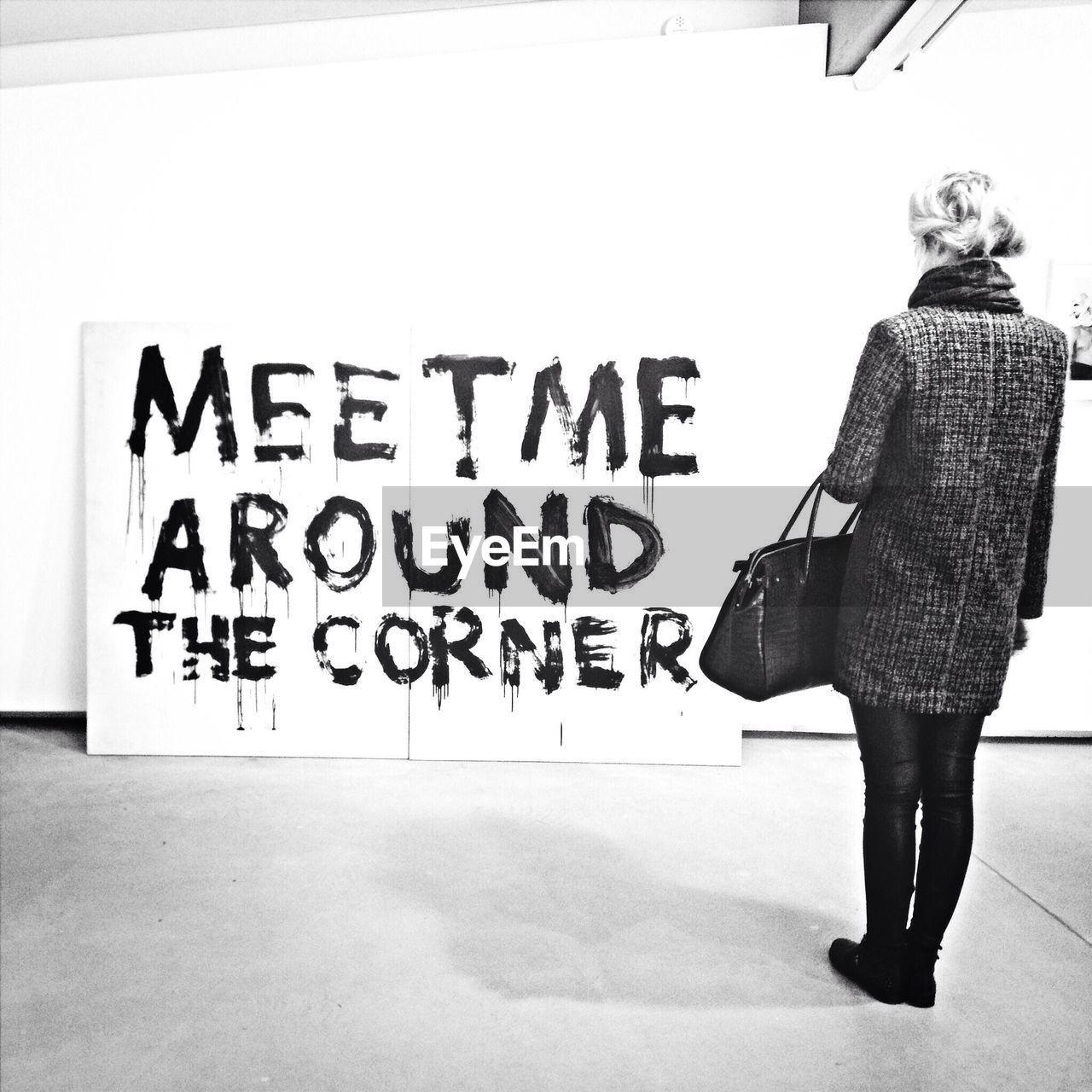 Full length rear view of woman looking at message on wall