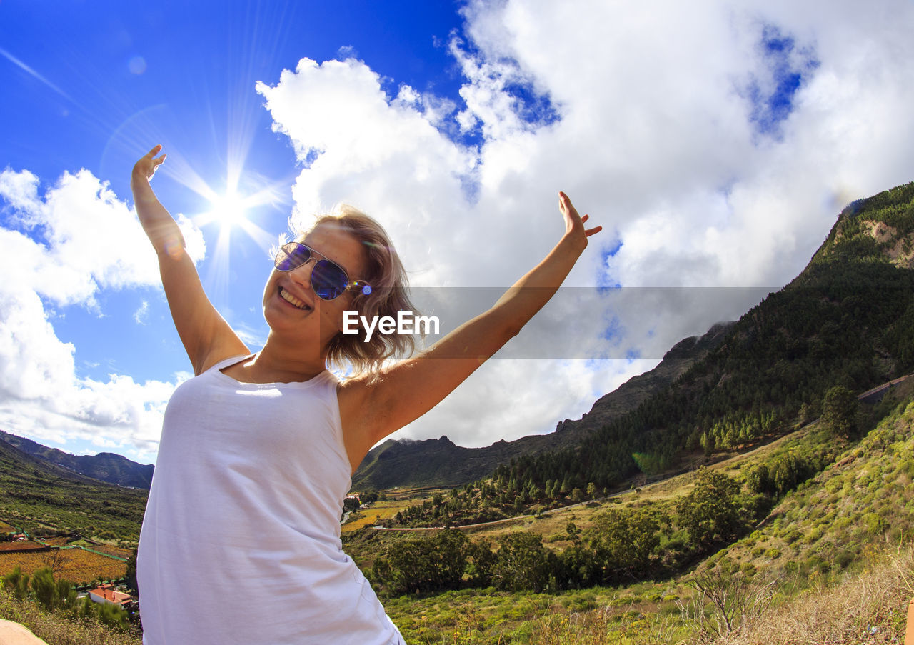 Happy woman with arms raised against sky