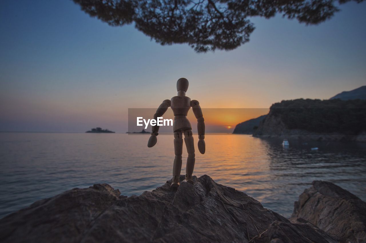 FULL LENGTH OF SHIRTLESS MAN STANDING ON SEA SHORE AGAINST SKY