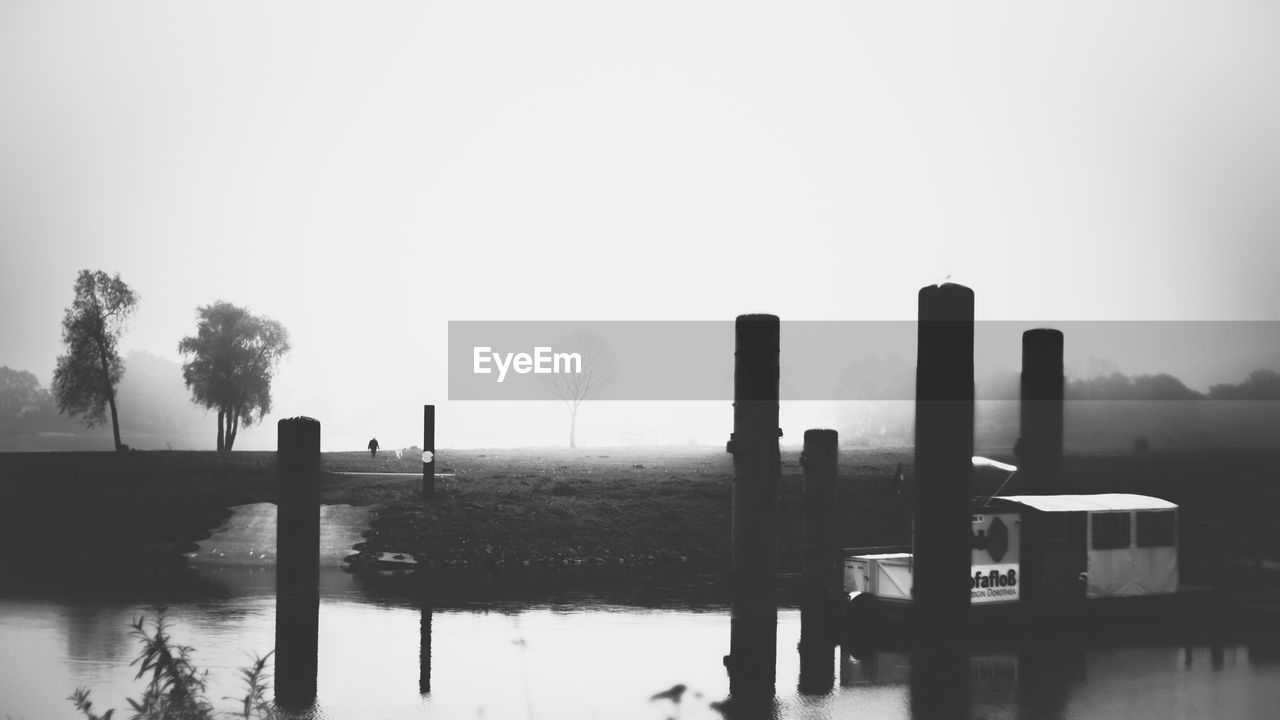 WOODEN POSTS IN LAKE AGAINST SKY