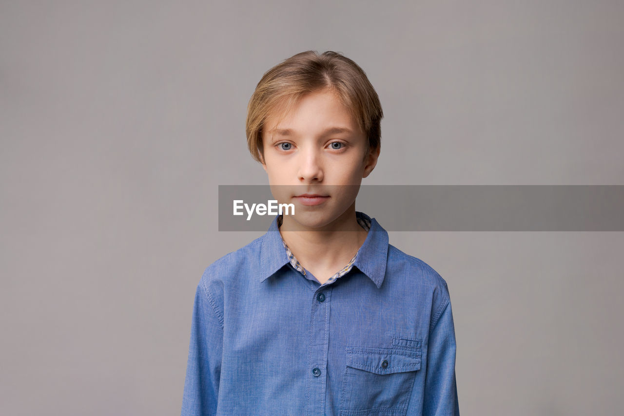 Happy millennial caucasian guy in blue shirt isolated on gray studio background