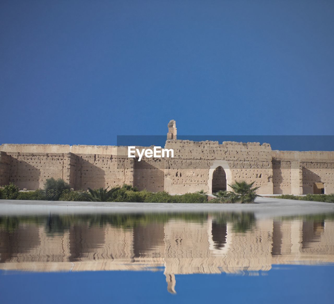 Reflection of building in water against clear blue sky