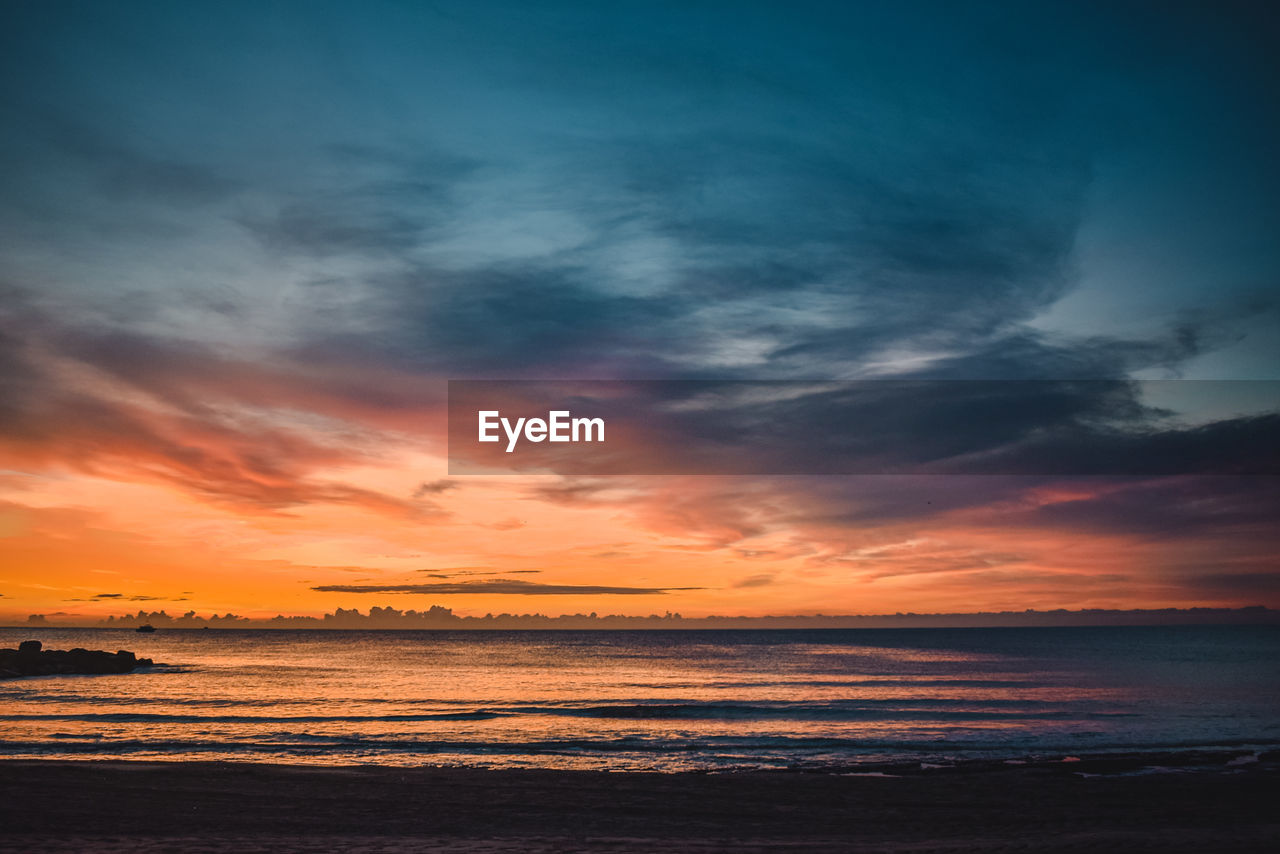 Scenic view of sea against dramatic sky during sunrise 