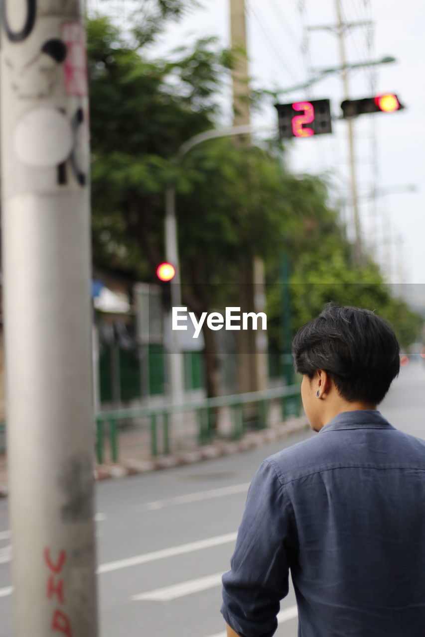 Rear view of man on standing on road in city