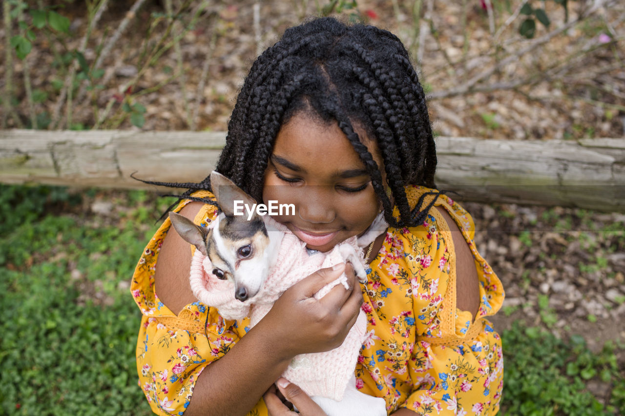 High angle view of smiling girl carrying cute chihuahua while standing in park