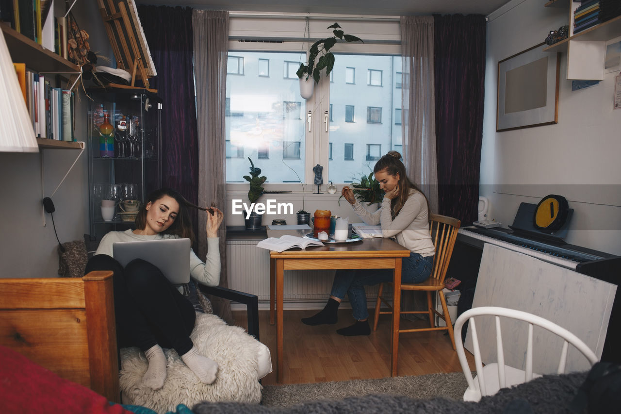 Young female roommates studying together in college dorm room