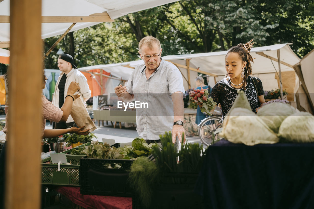 Customers buying organic vegetables from market