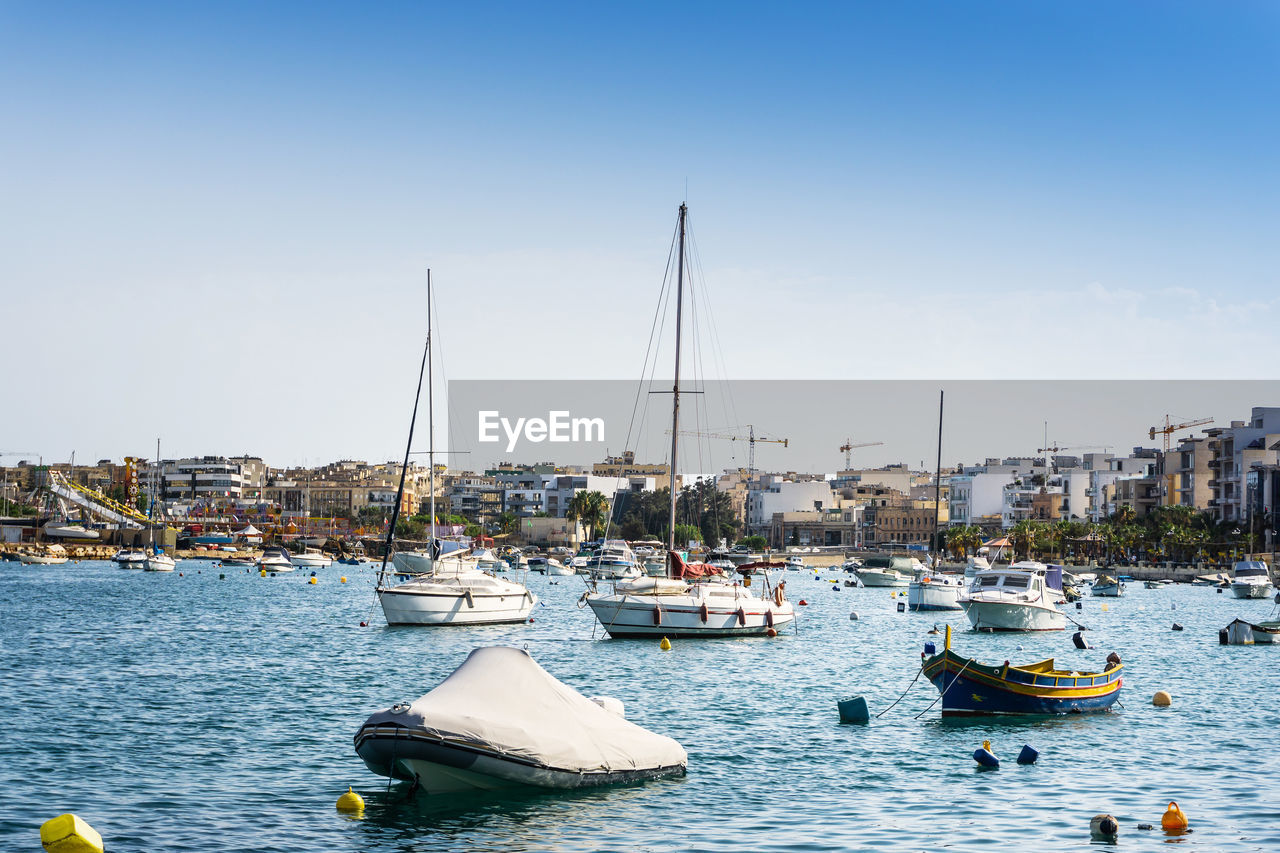 Sailboats moored at harbor against clear sky