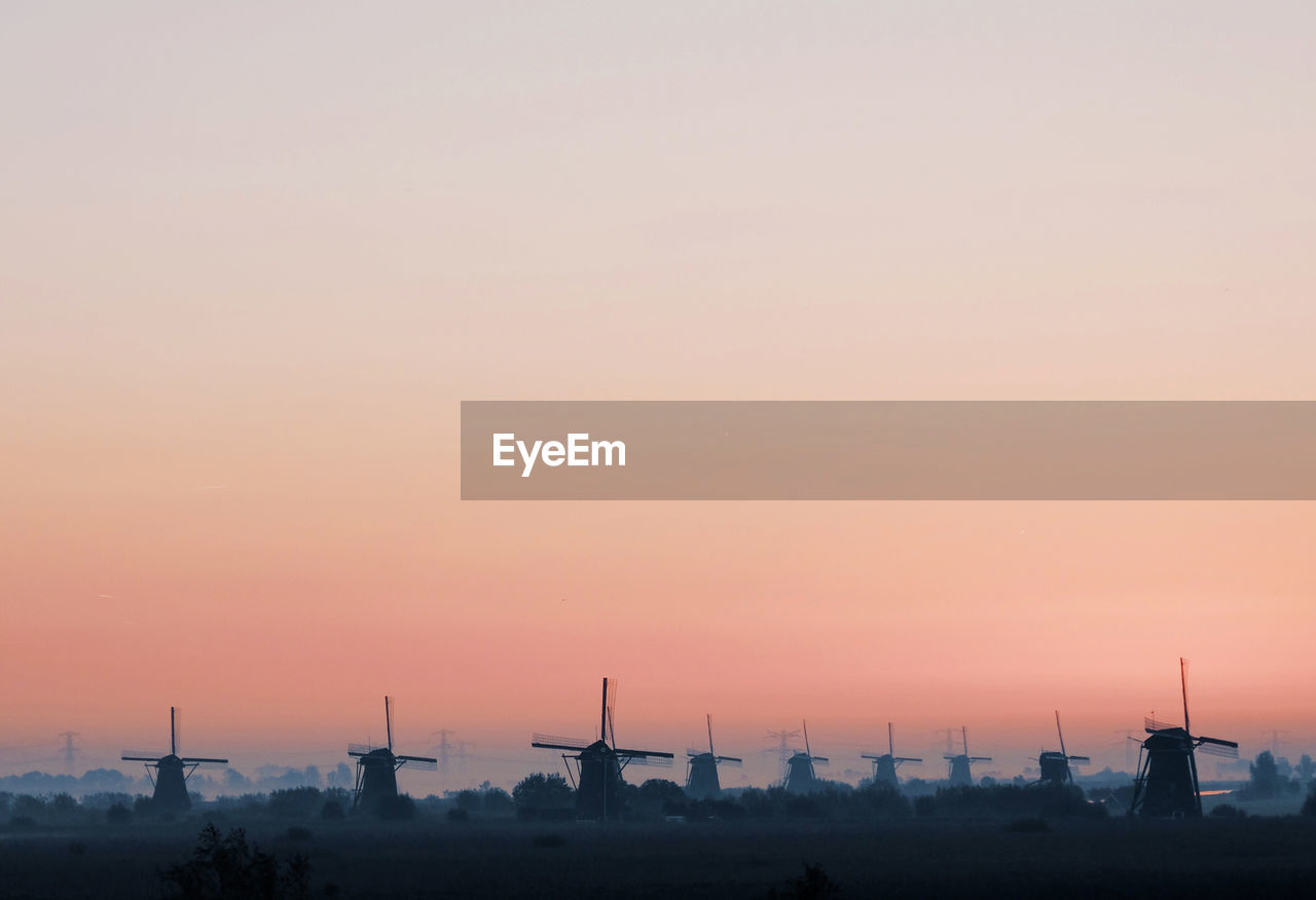 Traditional windmills against clear sky during sunset