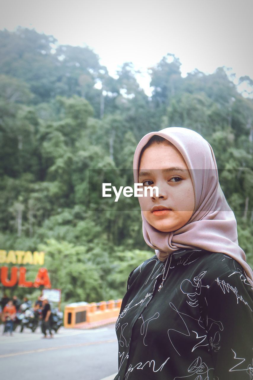 Portrait of young woman standing against mountain