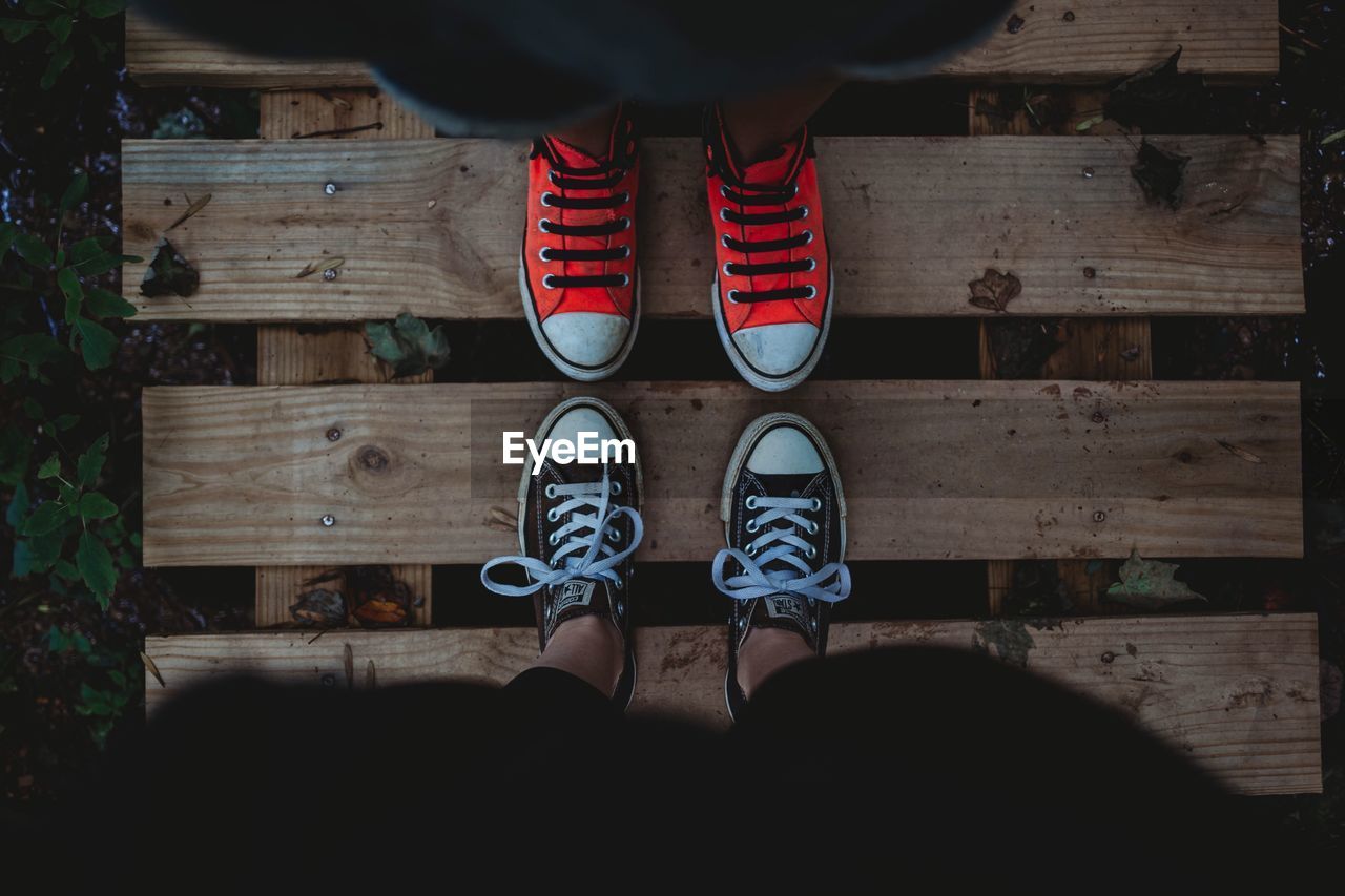 LOW SECTION OF PERSON STANDING BY WOODEN FLOOR