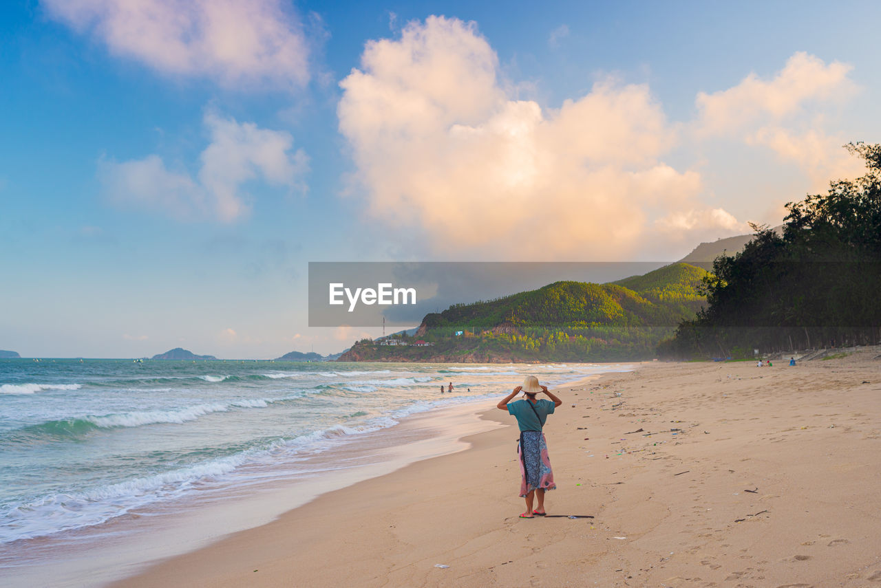 MAN STANDING ON BEACH AGAINST SKY