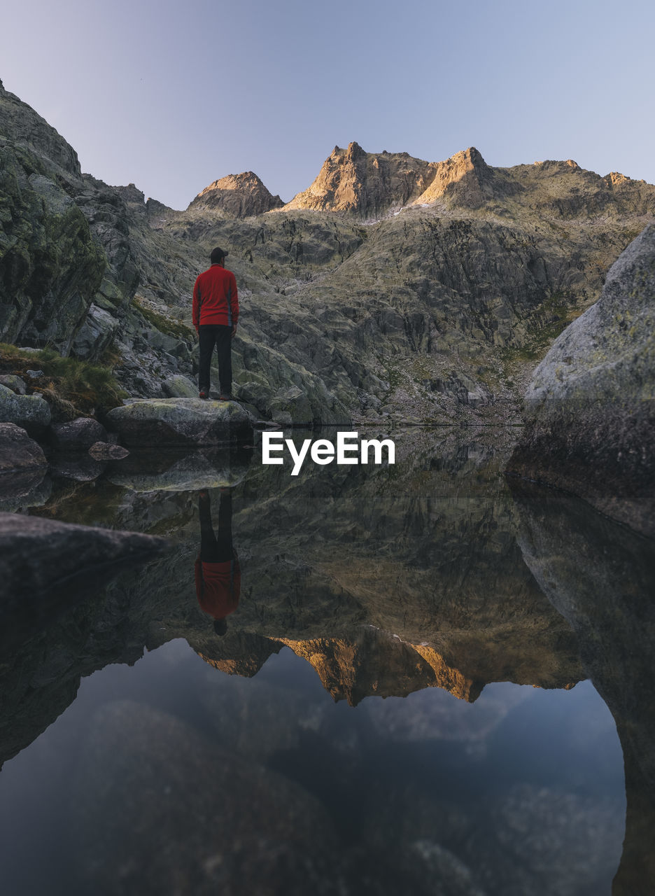 A young man stands on a rock during sunrise at sierra de gredos, spain