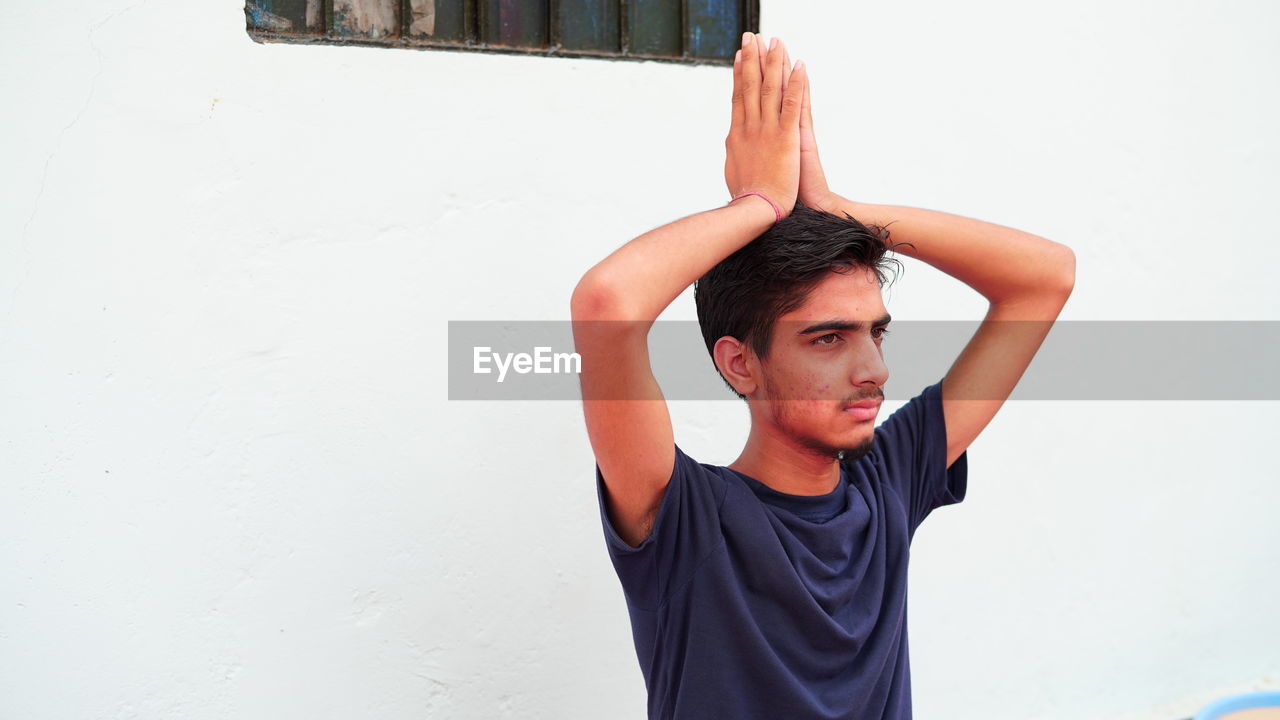 Portrait of young man standing against wall