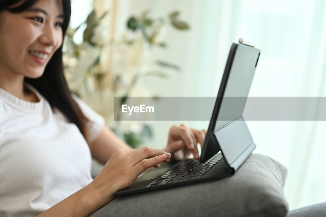 young woman using mobile phone while sitting at home