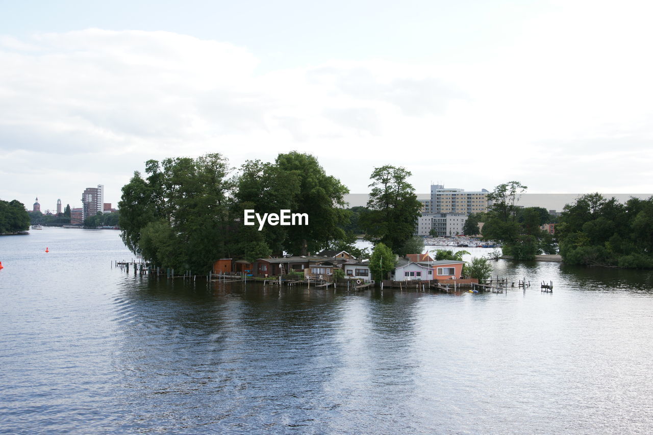 Stilt houses amidst river against sky